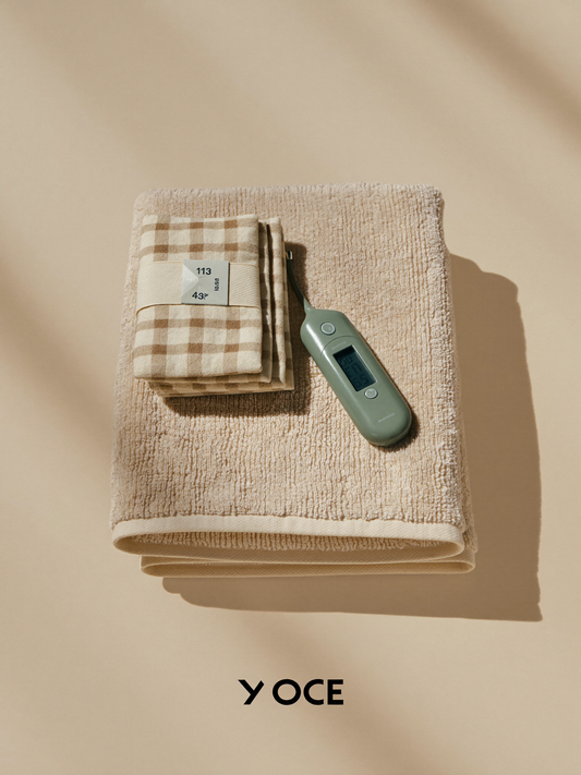 PLACEHOLDER (AI-generated) - Hooded towel, washcloths and thermometer arranged on cream