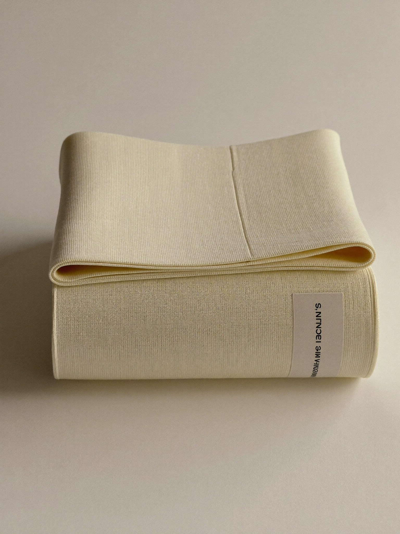 PLACEHOLDER (AI-generated) - Rolled cream postpartum support band on cream