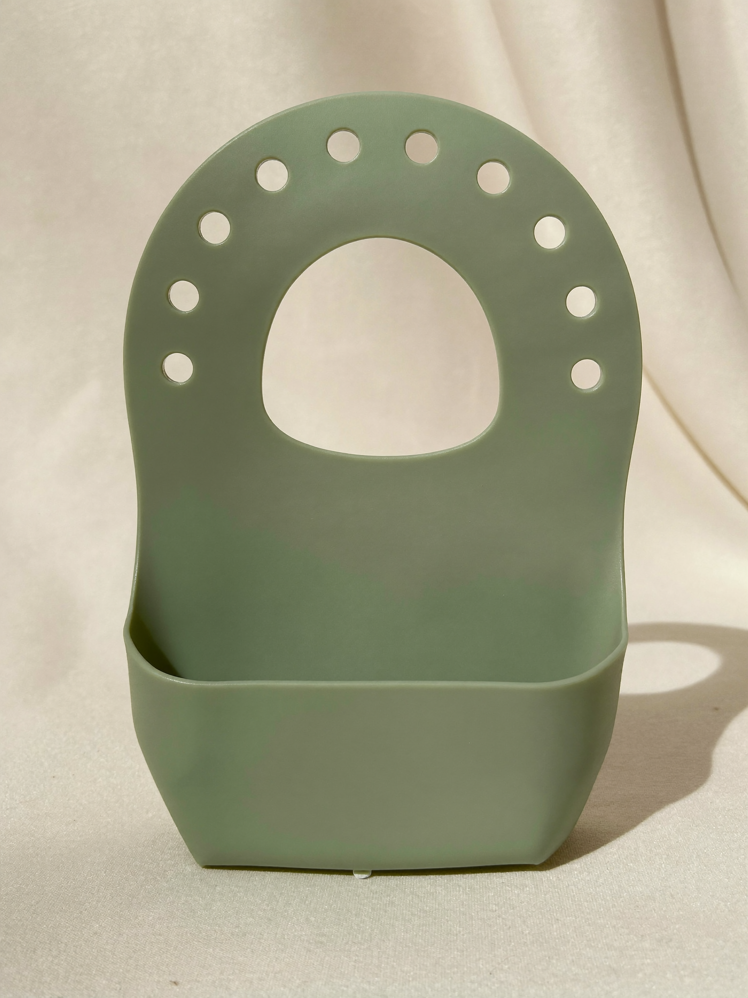 PLACEHOLDER (AI-generated) - Sage silicone bib with catch pocket on cream
