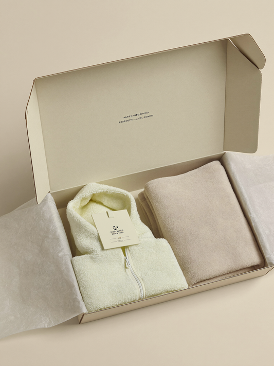 PLACEHOLDER (AI-generated) - Open cream gift box with folded baby items