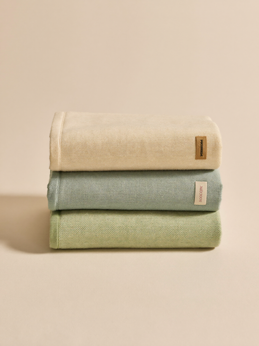 PLACEHOLDER (AI-generated) - Three folded muslin swaddles on cream