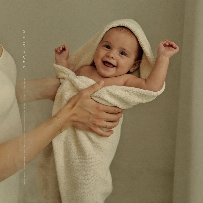 A parent wrapping a baby in a hooded towel after a bath