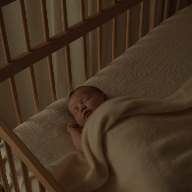 A sleeping baby swaddled in a muslin wrap